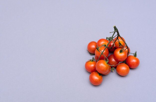 Pomodori biologici ciliegini rossi piccoli su sfondo grigio Concetto di alimentazione sana Cibo vegano