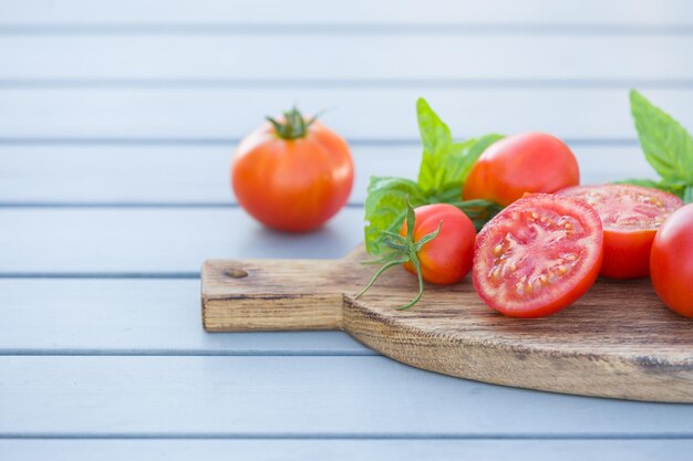 Pomodori biologici freschi con basilico su tavola di legno su tavolo grigio Concetto di cibo sano