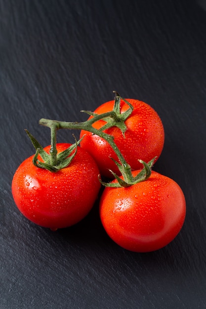 pomodori biologici sul bordo di ardesia nera con spazio di copia