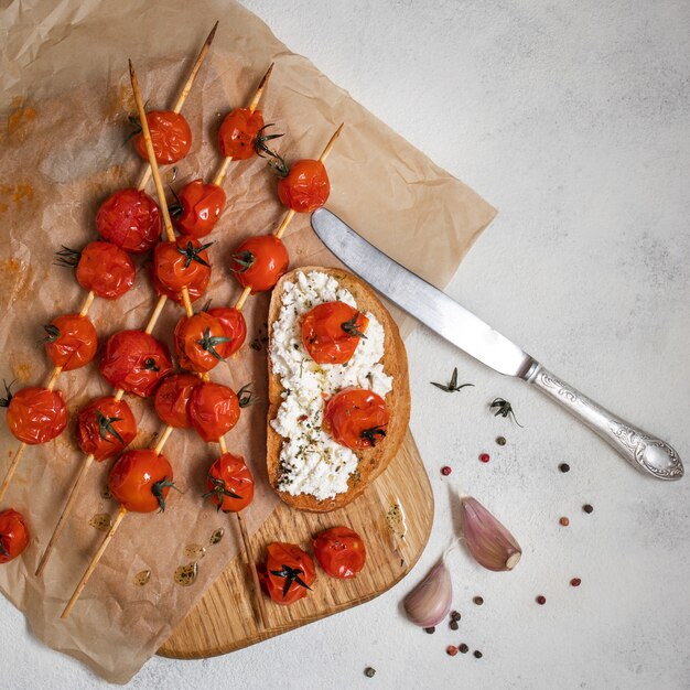 Pomodori ciliegia arrostiti sugli spiedi con la Bruschetta con i pomodori e il formaggio, vista superiore.