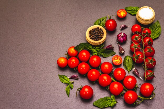 Pomodori ciliegia e spezie maturi su un fondo di pietra