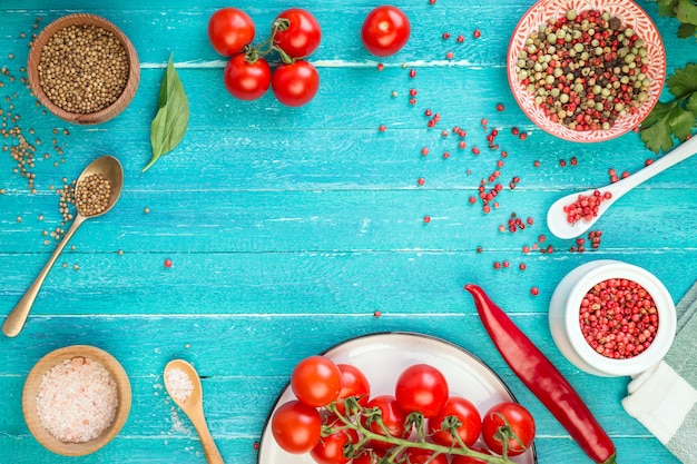 Pomodori ciliegia e spezie su una tavola di legno del turchese