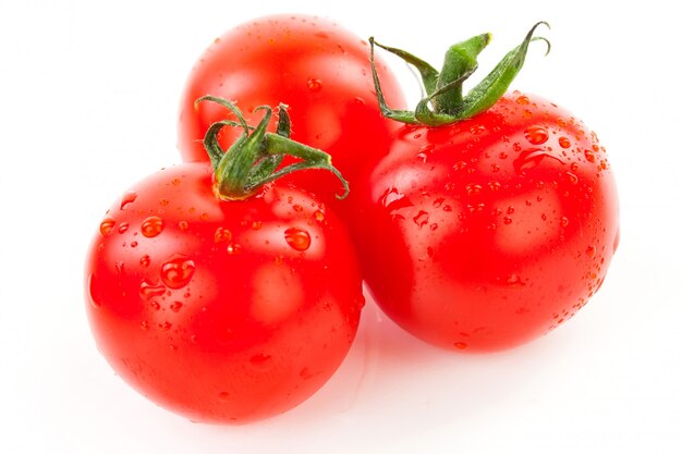 Pomodori ciliegia organici succosi con la foglia verde isolata