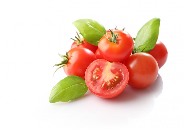 Pomodori ciliegia rossi maturi e basilico isolati su fondo bianco