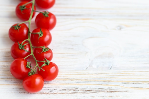 Pomodori ciliegia su una tavola di legno bianca