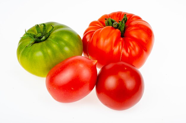 Pomodori colorati di diverse varietà su sfondo bianco. Foto dello studio.