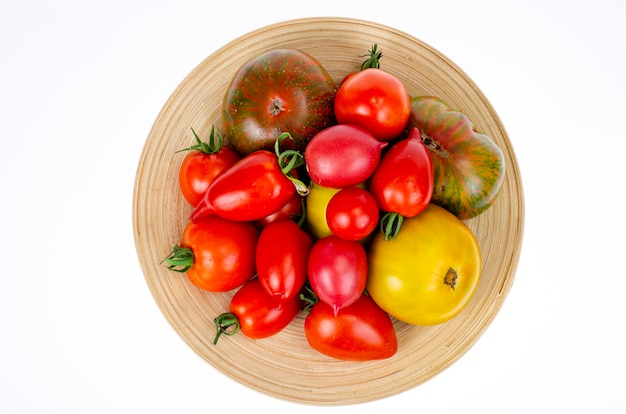 Pomodori colorati fatti in casa assortiti forme diverse sul piatto di legno. Foto dello studio.