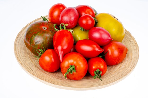 Pomodori colorati fatti in casa assortiti forme diverse sul piatto di legno. Foto dello studio.