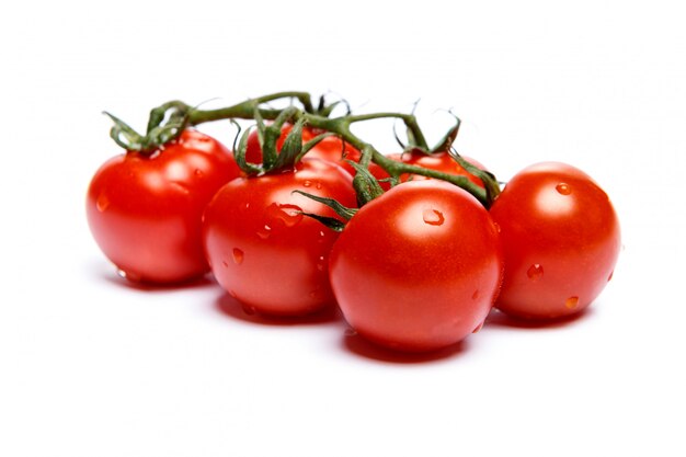 Pomodori di prugna con le foglie su bianco isolate