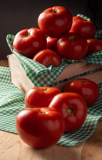 Pomodori disposti in un cesto su una tovaglia a scacchi e su un tavolo di legno