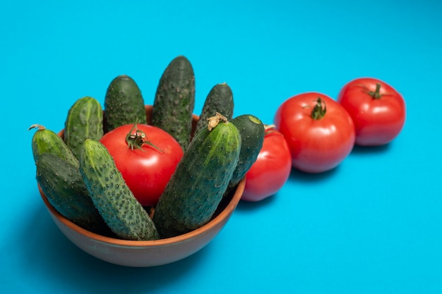 Pomodori e cetrioli maturi su sfondo blu