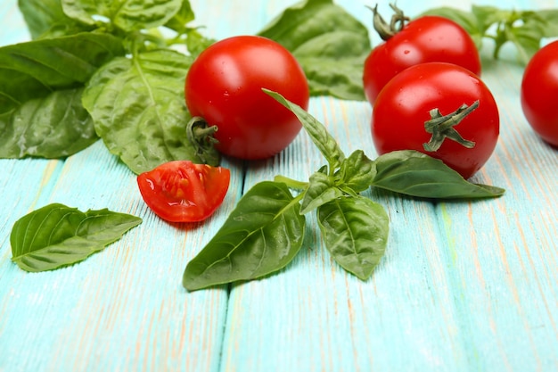 Pomodori freschi con basilico su un tavolo di legno da vicino