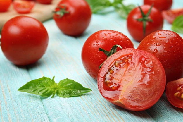 Pomodori freschi con basilico sulla tavola di legno si chiuda