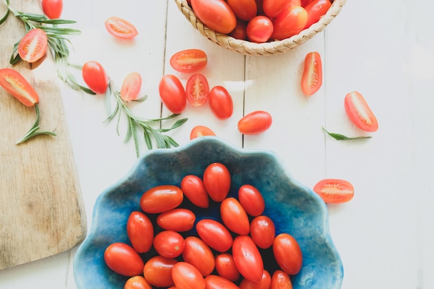 Pomodori freschi e rosmarino su bianco.