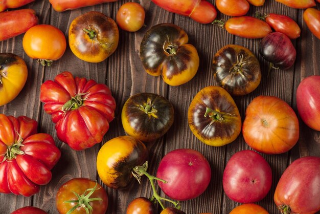 Pomodori freschi grandi e piccoli su fondo di legno scuro