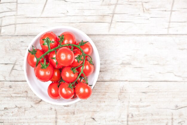 Pomodori freschi in ciotola bianca sul tavolo in legno rustico.