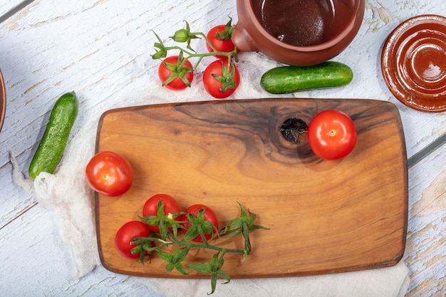 Pomodori freschi in un piatto di legno su bianco