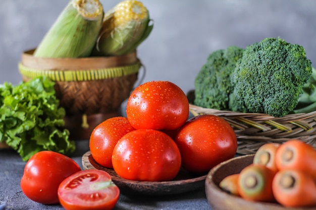 pomodori freschi in una ciotola, intorno a verdure, carota, pepe nero, mais, broccoli. Tagliare i pomodori. Raccolta pomodori.