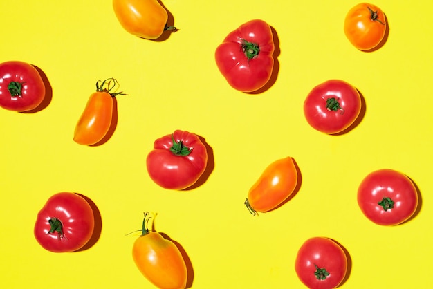 Pomodori gialli e rossi su sfondo giallo Vista dall'alto piatta Concetto minimo estivo Dieta vegana e vegetariana