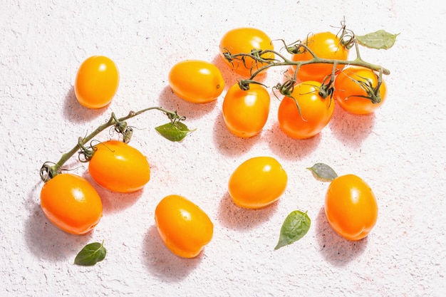 Pomodori giallo-arancio su fondo di intonaco chiaro. Verdure fresche mature, concetto di raccolta. Una luce dura alla moda, un'ombra scura, vista dall'alto