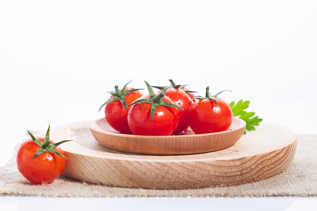 Pomodori in piatto di legno su fondo bianco