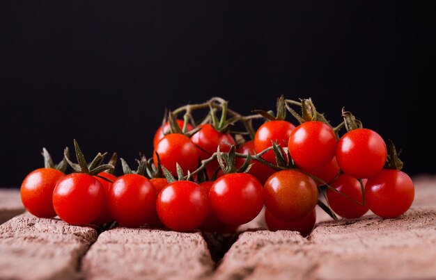 Pomodori in zolla di legno su priorità bassa nera