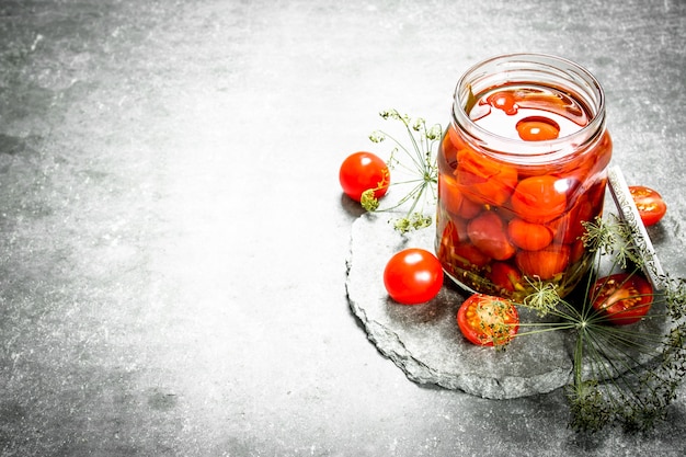 Pomodori marinati alle erbe. Su uno sfondo di pietra.