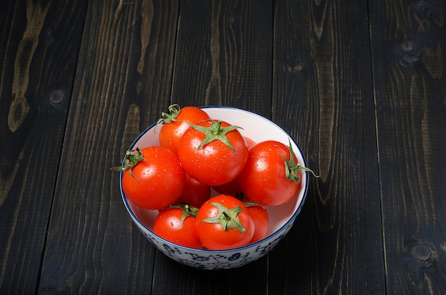 Pomodori maturi e freschi su fondo di legno rustico scuro.