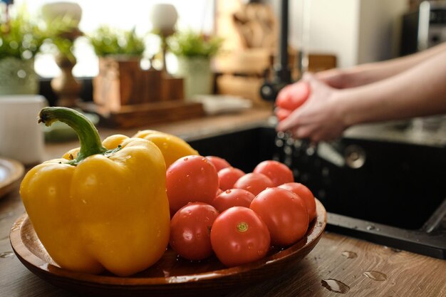 Pomodori maturi freschi e puliti e peperoni gialli sul piatto di legno