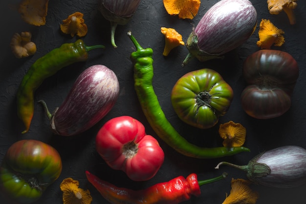 Pomodori melanzane peperoncino e finferli su un tavolo grigio