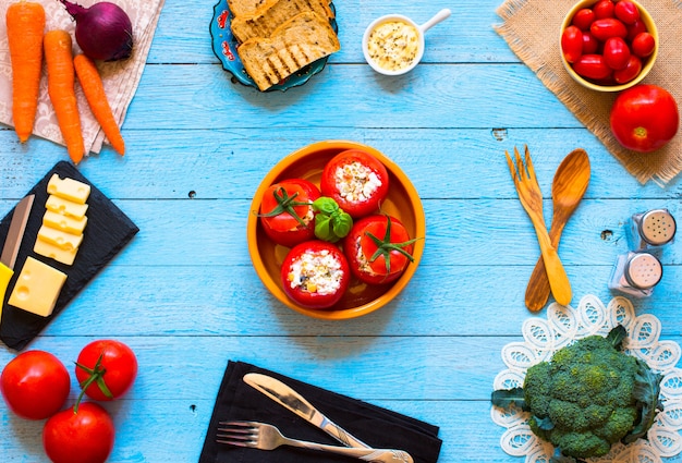 Pomodori ripieni con formaggio e verdure diverse su un tavolo di legno