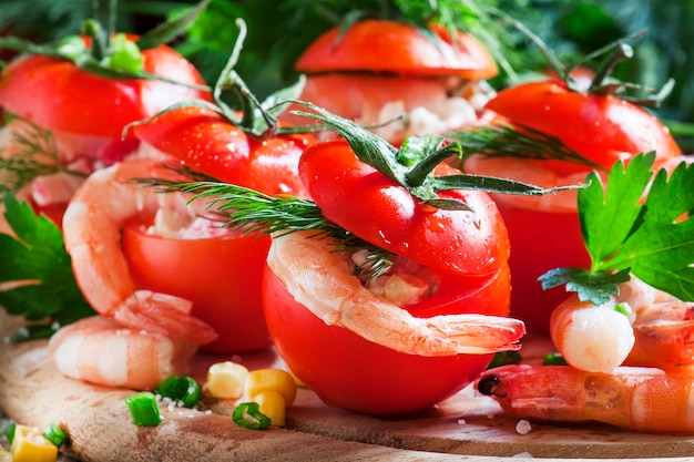 Pomodori ripieni di carne di gamberi e mais su un fuoco selettivo piatto di legno