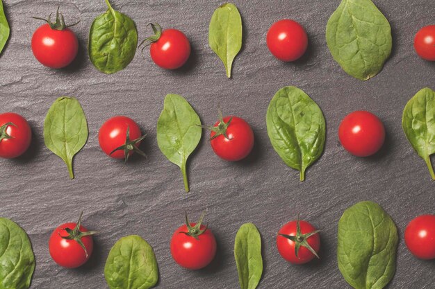 Pomodori rossi ciliegia e foglie di insalata verde su uno sfondo di ardesia