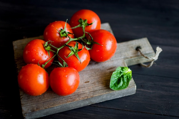 Pomodori rossi del ramo sul tavolo scuro