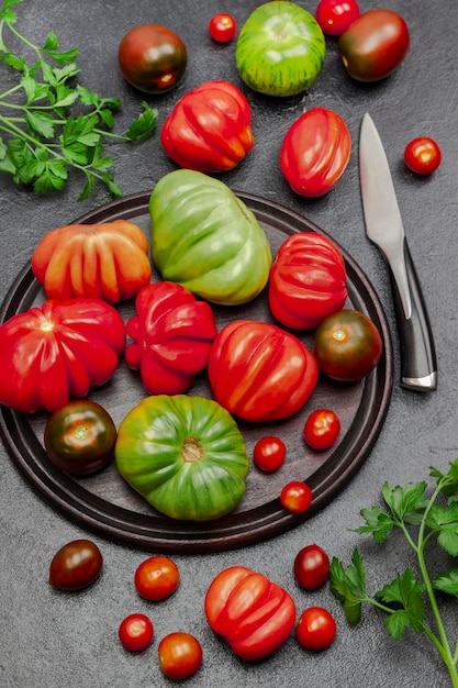 Pomodori rossi e verdi sul tagliere e sul tavolo Rametti di prezzemolo e coltello