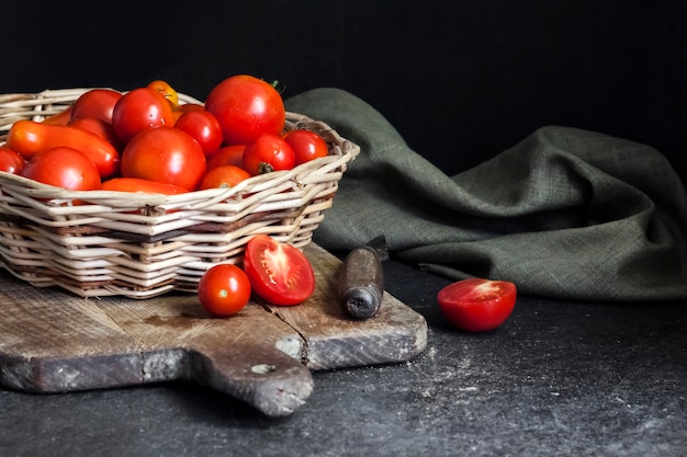 Pomodori rossi freschi in cesto di vimini su sfondo nero