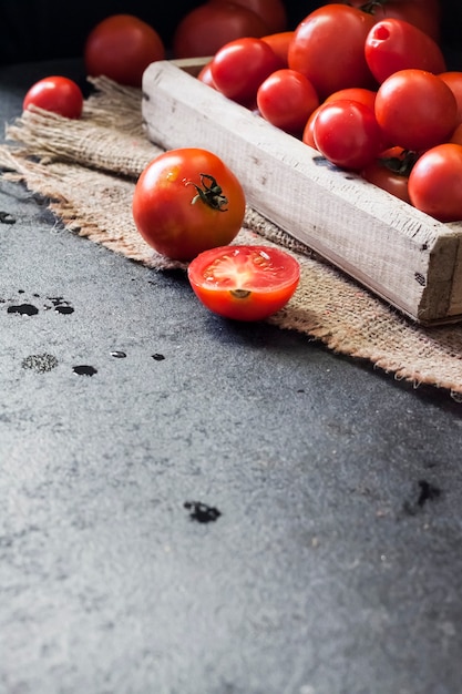 Pomodori rossi freschi in scatola di legno su sfondo nero. Copia spazio