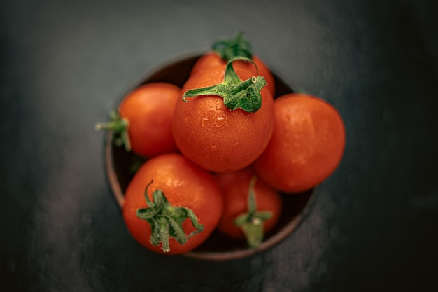 Pomodori rossi maturi cocktail in una ciotola su un tavolo nero Rosso e nero Verdure succose Prodotti rossi