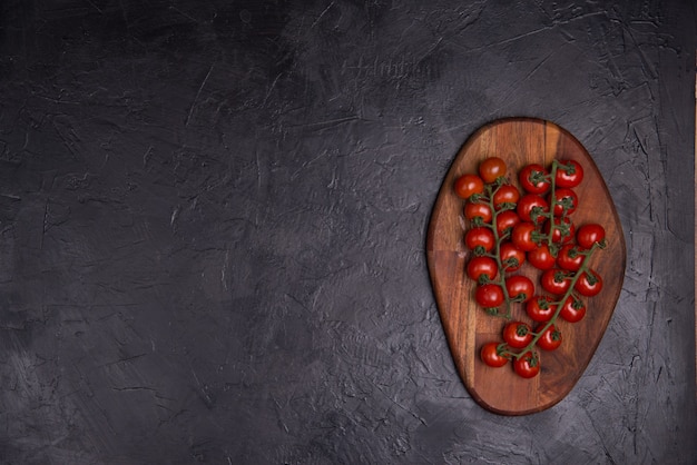 Pomodori rossi maturi su un tavolo di legno con sfondo nero. Vecchio stile rustico scuro.