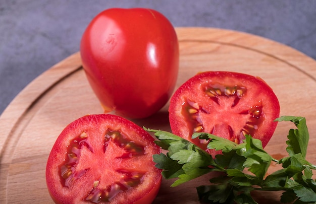 Pomodori rossi su un tagliere con un rametto di prezzemolo