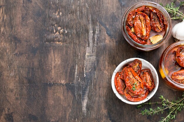 Pomodori seccati al sole con olio d'oliva in un barattolo su legno