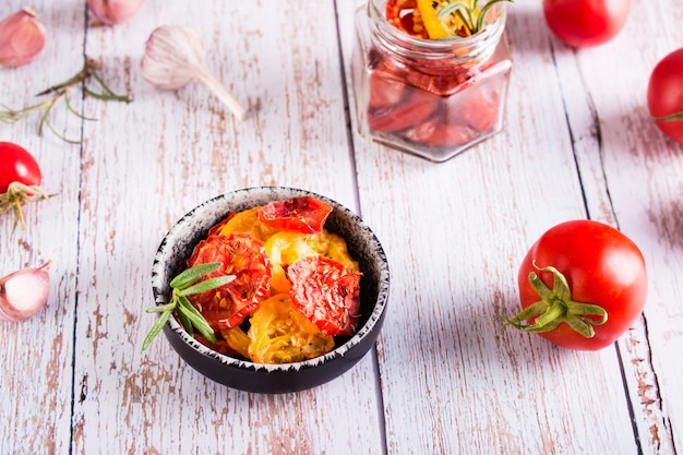 Pomodori secchi con spezie ed erbe aromatiche in una ciotola e verdure fresche sul tavolo Spuntino fatto in casa