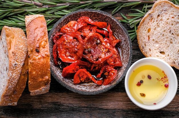 Pomodori secchi in ciotola di legno Fette di Ciabatta su tavola di legno con olive tom essiccate