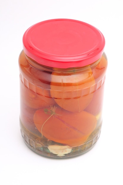 Pomodori sott'aceto in barattolo di vetro su fondo bianco isolato