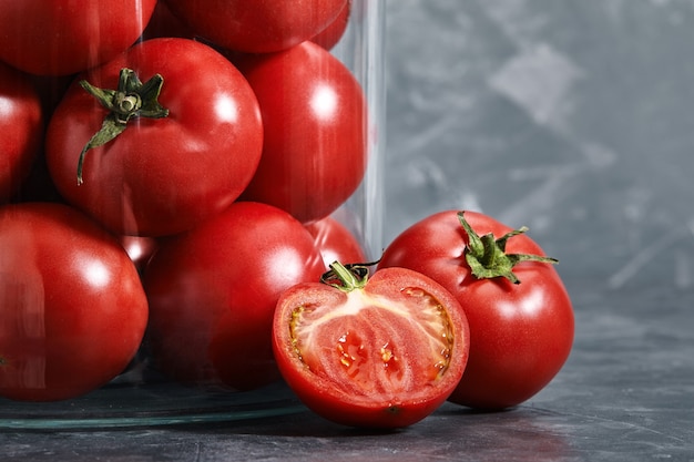 Pomodori succosi in uno sfondo grigio vaso di vetro. Verdure fresche, succose e sane. Vista dall'alto.