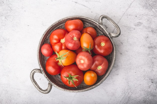 Pomodori succosi, maturi in ciotola di metallo con grappoli sul tavolo di pietra