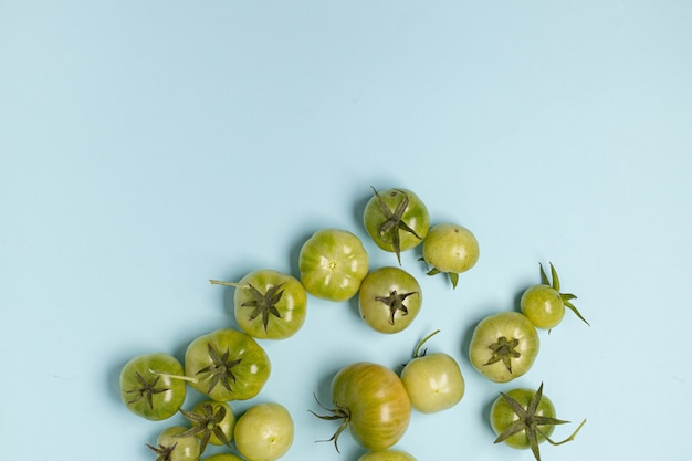 Pomodori verdi freschi di diverse dimensioni mucchio su uno sfondo blu con copia spazio