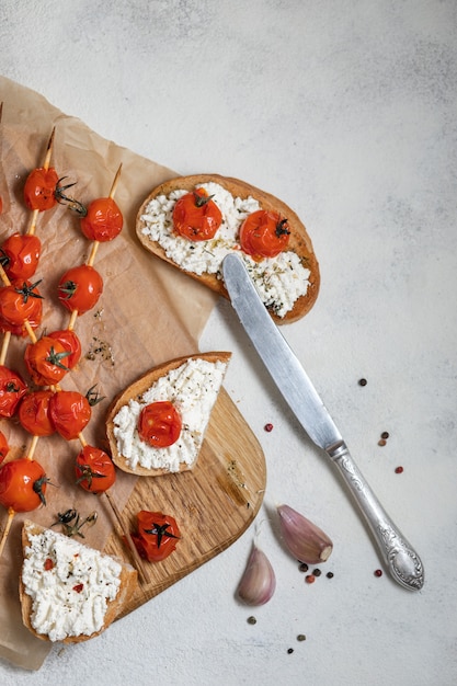 Pomodorini alla griglia su spiedini, su carta da forno. Bruschetta italiana con pomodori e formaggio