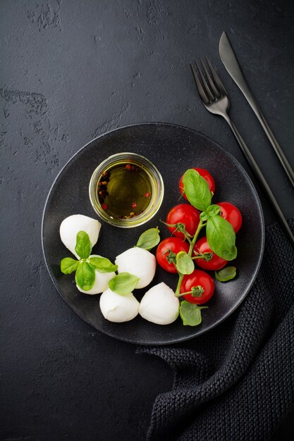 Pomodorini, basilico, mozzarella e olio d'oliva in banda nera su oscurità