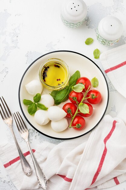 Pomodorini, basilico, mozzarella e olio d'oliva su bianco